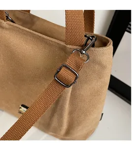 Detail of adjustable detachable shoulder strap and hardware on brown canvas tote bag