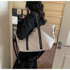 Detail of trendy tote bag featuring silver studs on black straps and minimalist design