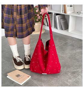 Detail of red tote bag with white star pattern and long shoulder straps for daily use