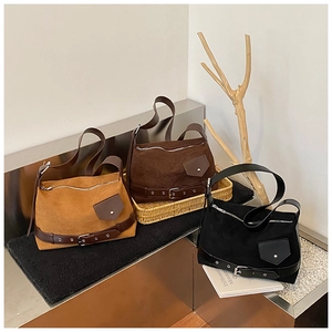 Trois sacs bandoulière en daim marron et noir sur un présentoir au style nordique