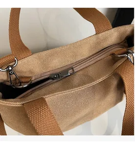 Close-up of smooth metal zipper and durable canvas handle on this khaki tote bag