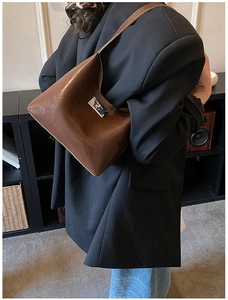 Detail view of a dark brown PU leather shoulder bag with a silver metallic twist lock