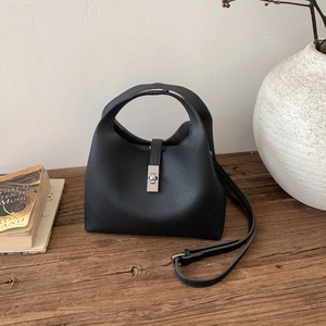 Detail of black pebble leather bucket bag featuring silver twist lock and smooth top handle