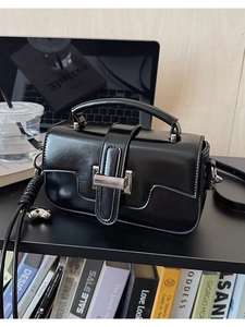Detailed close-up of glossy black leather tote with elegant silver metal buckle