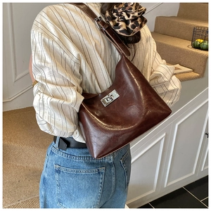 Detailed view of dark brown leather shoulder bag with silver square twist lock closure