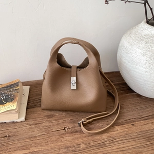 Detail of dark camel litchi grain leather bucket bag with silver metal rotating lock clasp
