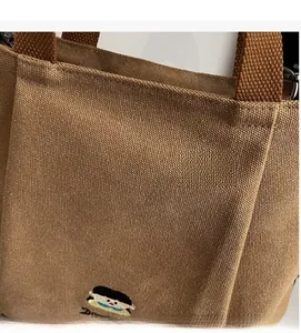Detail of premium brown canvas fabric texture and cartoon embroidery on high capacity tote