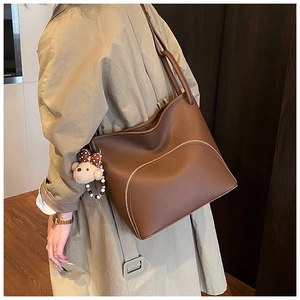 Close-up of brown lychee leather tote bag with U-shaped zipper and cute bear charm