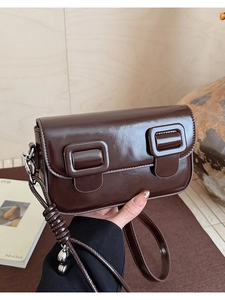 Detailed macro of vintage dark brown glossy leather shoulder bag with square buckles