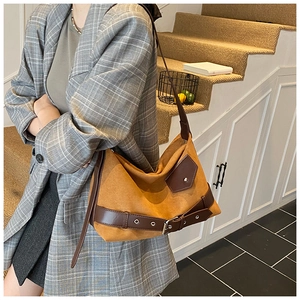Sac sous le bras en suédine marron avec détails de lanières sur un modèle en costume