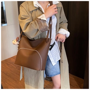 Brown litchi grain tote bag with white zipper detail and cute plush dog charm