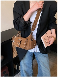Close-up of brown multi-pocket crossbody bag with metallic buckles on a model