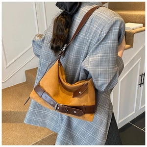 Détail d'un sac cabas en daim moutarde avec anses en cuir marron et boucles métalliques