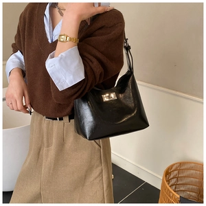 Detail of a black oil-wax leather hobo bag with a silver twist-lock on a model