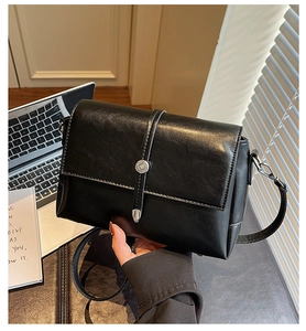 Détail d'un sac à main noir rectangulaire avec boucles argentées et bandoulière réglable