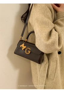 Detail shot of mini dark brown patent leather handbag with gold M and G metal charms