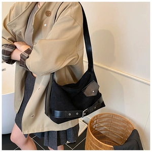 Détail du sac cabas en daim noir avec boucles argentées et bandoulière sur l'épaule