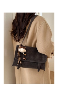 Detail of vintage matte tote bag with shoulder strap and plush bear charm on coat
