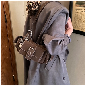 Close-up of dark brown canvas crossbody bag with white stitching and silver buckles