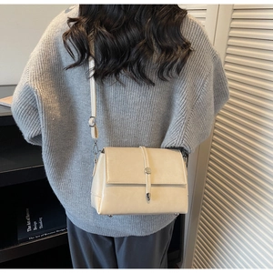 Minimalist beige crossbody square bag with metal clasp shown in a lifestyle setting