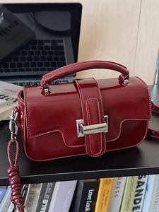 Minimalist deep red leather shoulder bag with silver buckle in a modern lifestyle setting