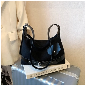 Gros plan d'un sac cabas noir avec boucle argentée et détails en cuir sur un livre