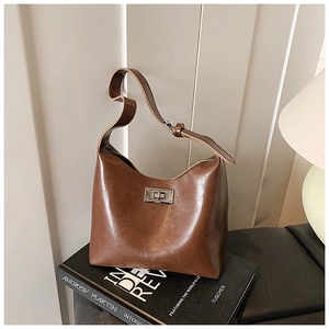 Close-up of vintage brown leather bucket bag with silver twist lock on a book