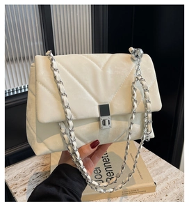 Detail of V-quilted faux leather bag with silver square lock and pearl chain decoration