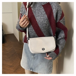 Detailed close-up of a cream white lychee texture shoulder bag with silver turn-lock