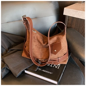 Détail du sac hobo en daim marron café avec boucle argentée et patchs décoratifs en cuir