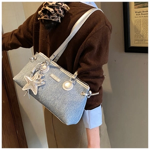 Details der blauen Denim-Achseltasche mit silbernem Lederbesatz und Stern-Anhänger