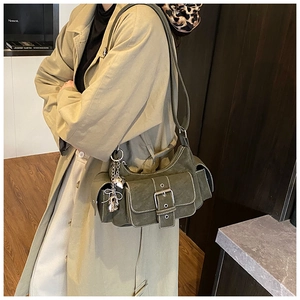 Detail of dark green multi-pocket utility bag with silver buckles and matte finish texture