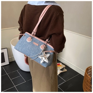 Detail der Denim-Schultertasche mit rosa Rand, Metallnieten und einem silbernen Stern