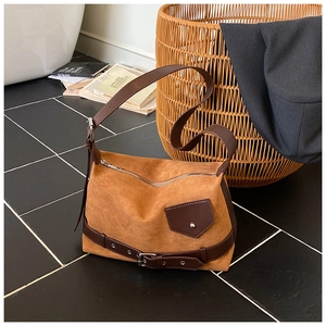 Détail d'un sac à bandoulière en daim moutarde avec sangle en cuir sur marbre