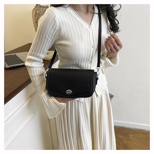 Detail shot of black lychee grain leather underarm bag with silver round twist lock buckle