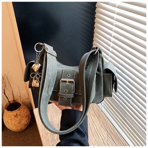 Close-up of retro green shoulder bag featuring metal buckle and heart-shaped pendant detail