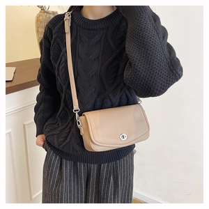 Detail showing khaki faux leather small square bag with silver twist lock on shoulder