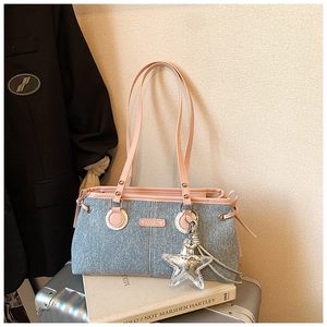 Nahaufnahme der Jeans-Schultertasche mit rosa Besatz und silbernem Stern-Anhänger