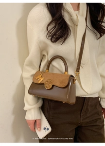 Close-up of retro brown shoulder bag with gold G-lock and suede flap detail