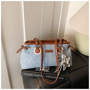 Detail der blauen Denim-Tasche mit braunem Lederbesatz und silbernem Stern-Anhänger