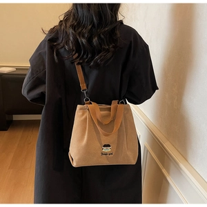 Detailed close-up of brown corduroy tote bag featuring docile girl cartoon embroidery