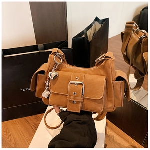 Close-up of caramel leather underarm bag with Y2K metal heart pendant and buckled pocket