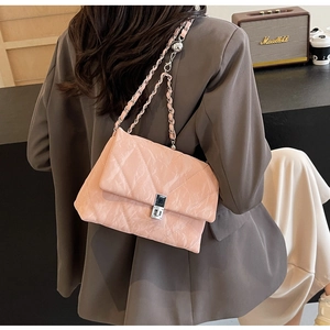 Detailed close-up of quilted pink shoulder bag with silver chain strap and metal lock