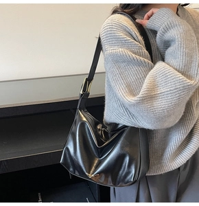 Vue détaillée d'un sac sous le bras noir minimaliste avec boucles dorées chic