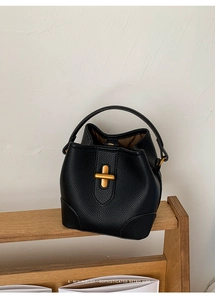 Detail view of black lychee grain leather bucket bag with gold T-bar metal twist lock