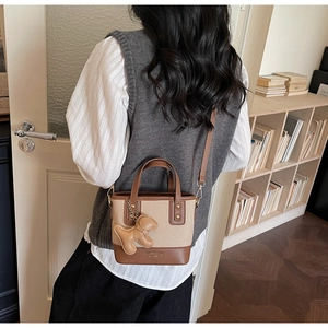 Detail of canvas bucket bag with leather trim and puppy charm in a cozy home setting