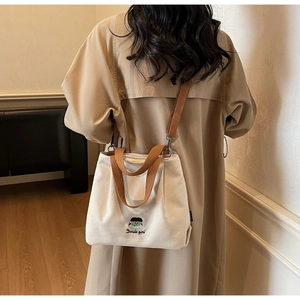 Detailed back view of a cream canvas tote bag featuring embroidered cartoon and text details