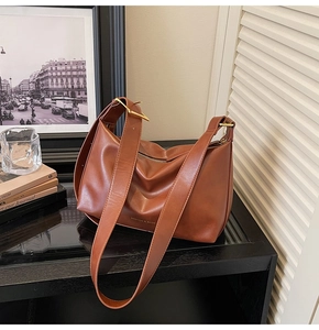 Gros plan d'un sac à bandoulière en cuir marron rétro avec des boucles dorées