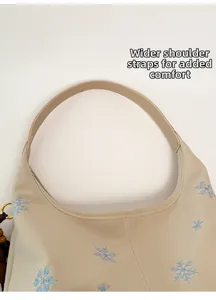 Nahaufnahme der cremefarbenen Tasche mit Schneeflocken-Stickerei und breitem Gurt