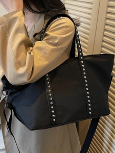 Fashionable black large capacity tote bag with silver rivets and nylon strap on model